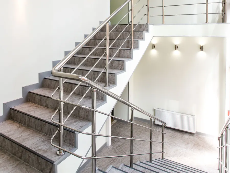Helles Treppenhaus eines Mehrfamilienhauses mit Metallgeländer. Symbolbild, kein dokumentierter Auftrag.